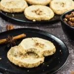 Broken pecan shortbread cookie showing the crisp crumb and pecan pieces.