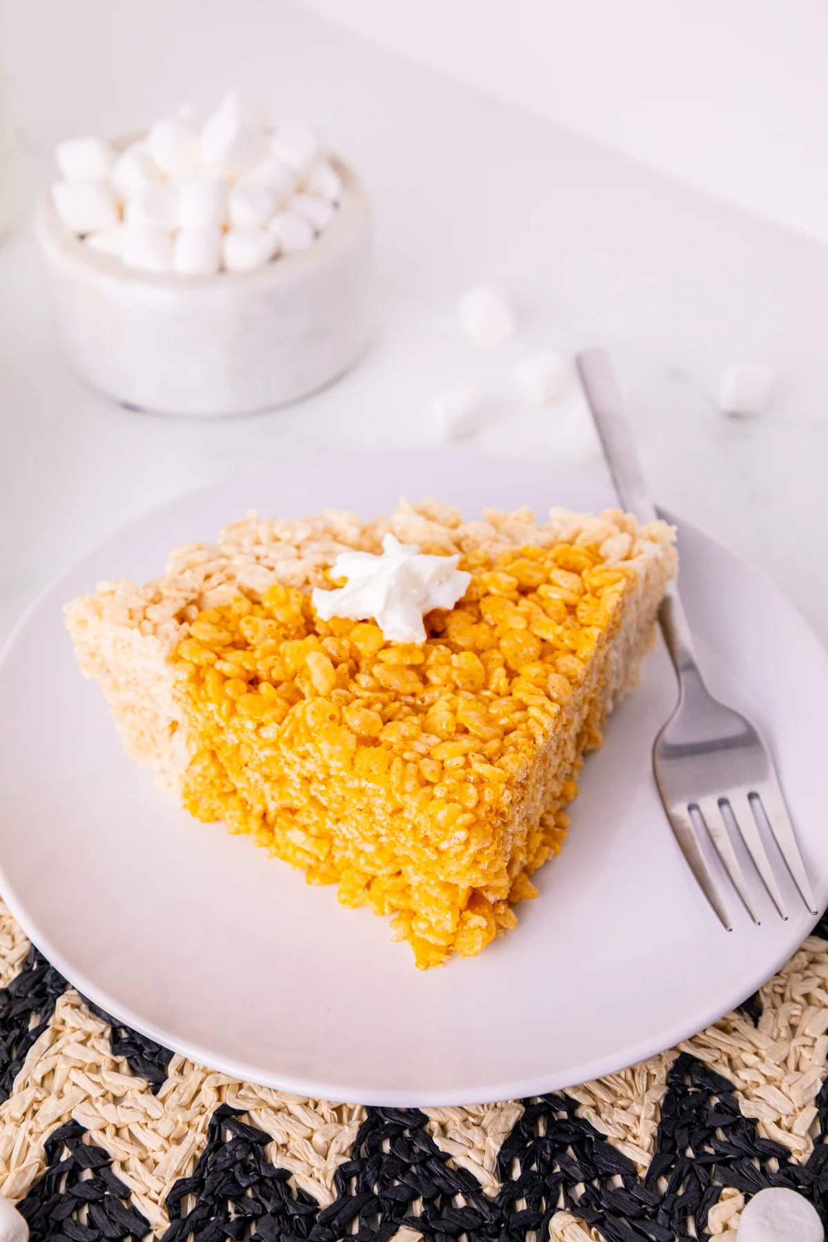 Close-up of a pumpkin-colored Rice Krispie treat wedge with a plain cereal crust.