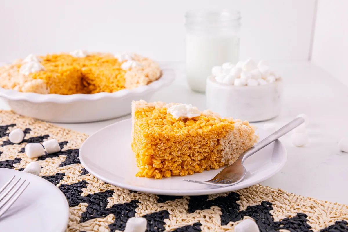 A wedge of Pumpkin Pie Rice Krispie Treats on a plate with whipped topping.