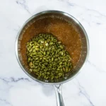 Toasted pepitas stirred into bubbling brown sugar and honey syrup.