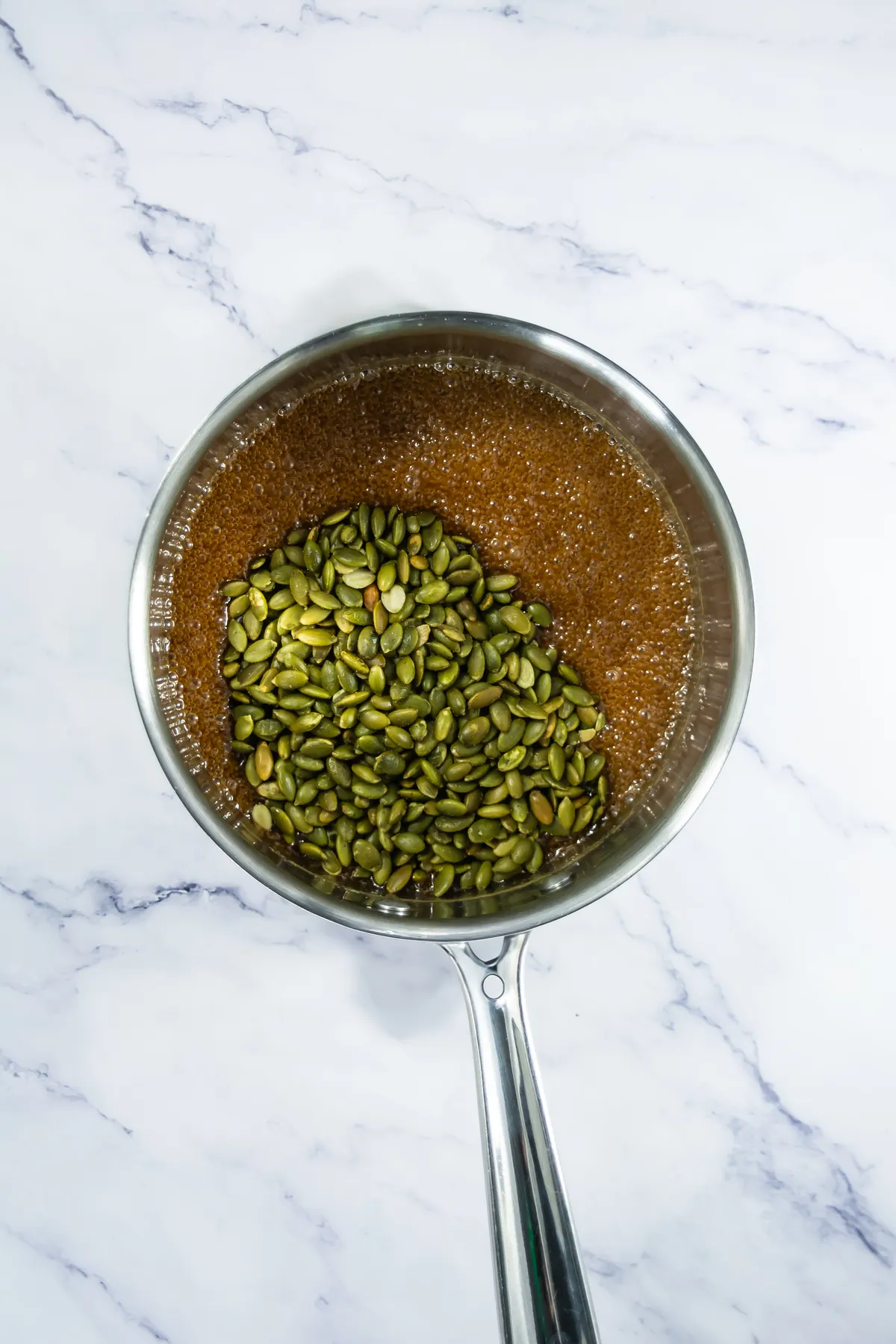 Toasted pepitas stirred into bubbling brown sugar and honey syrup.