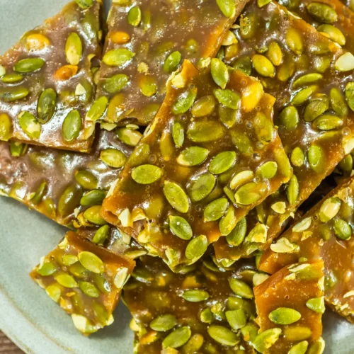 Close-up of pumpkin seed brittle pieces with glossy honey caramel and toasted pepitas.