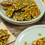 Stack of finished pumpkin seed brittle pieces on a green plate.