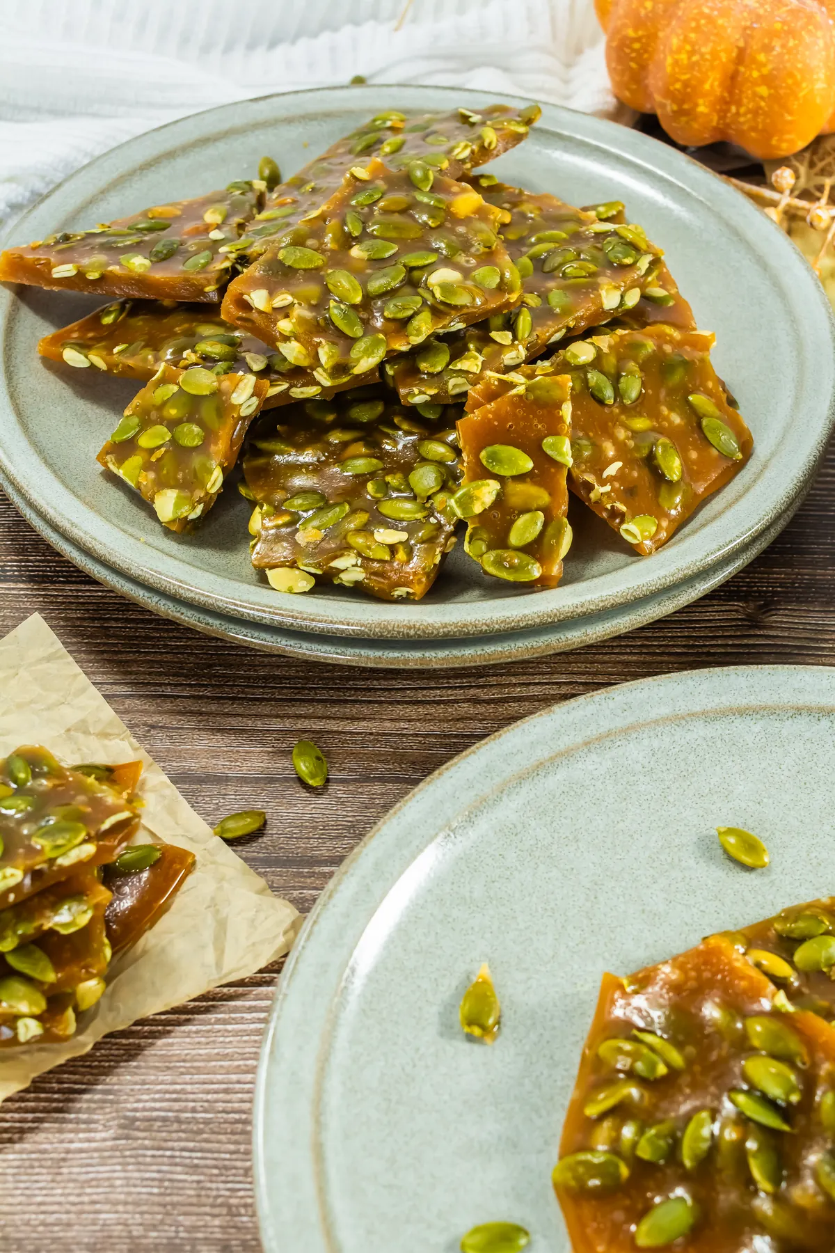 Stack of finished pumpkin seed brittle pieces on a green plate.