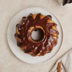Overhead view of a small cinnamon swirl Bundt cake topped with chocolate drizzle.