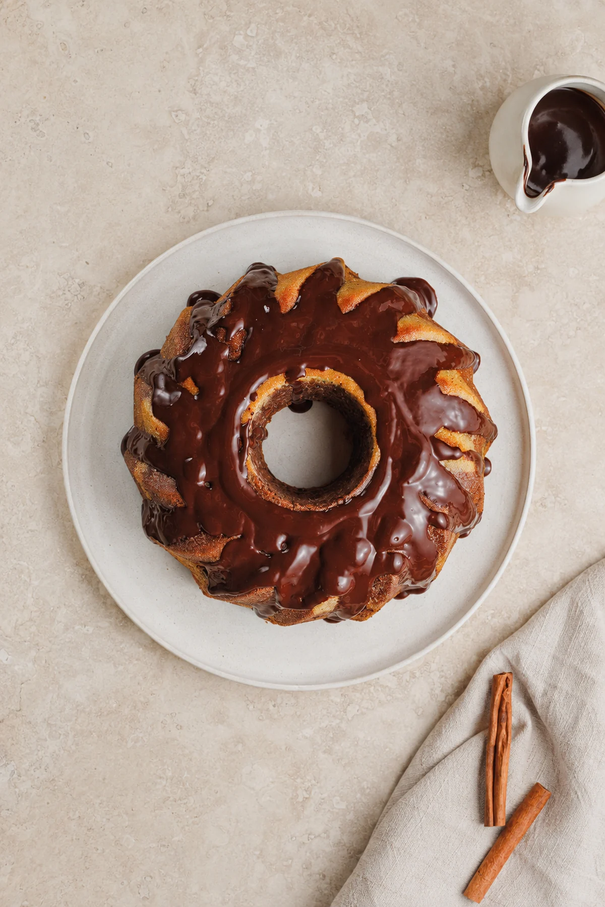 Overhead view of a small cinnamon swirl Bundt cake topped with chocolate drizzle.