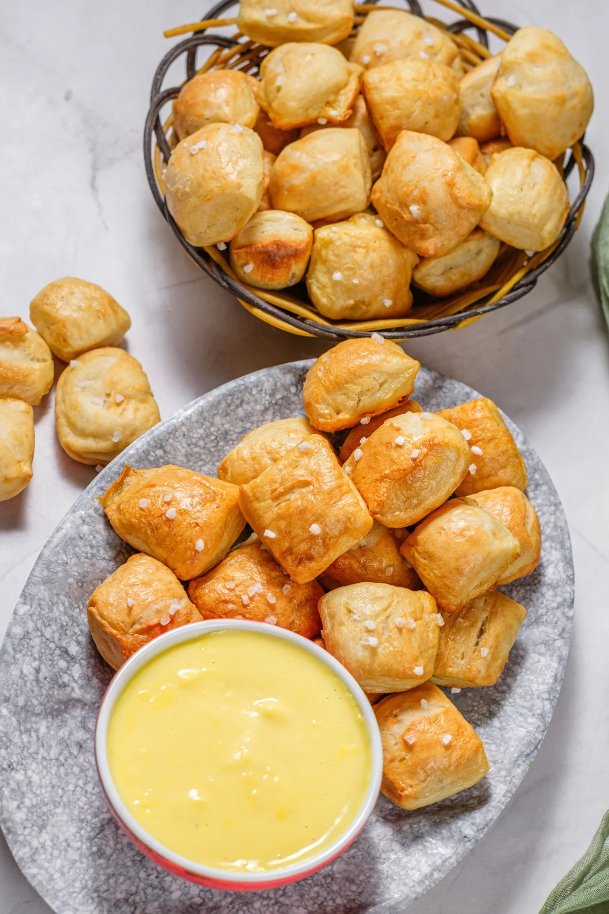 A platter of golden soft pretzel bites served with a bowl of cheese dip.