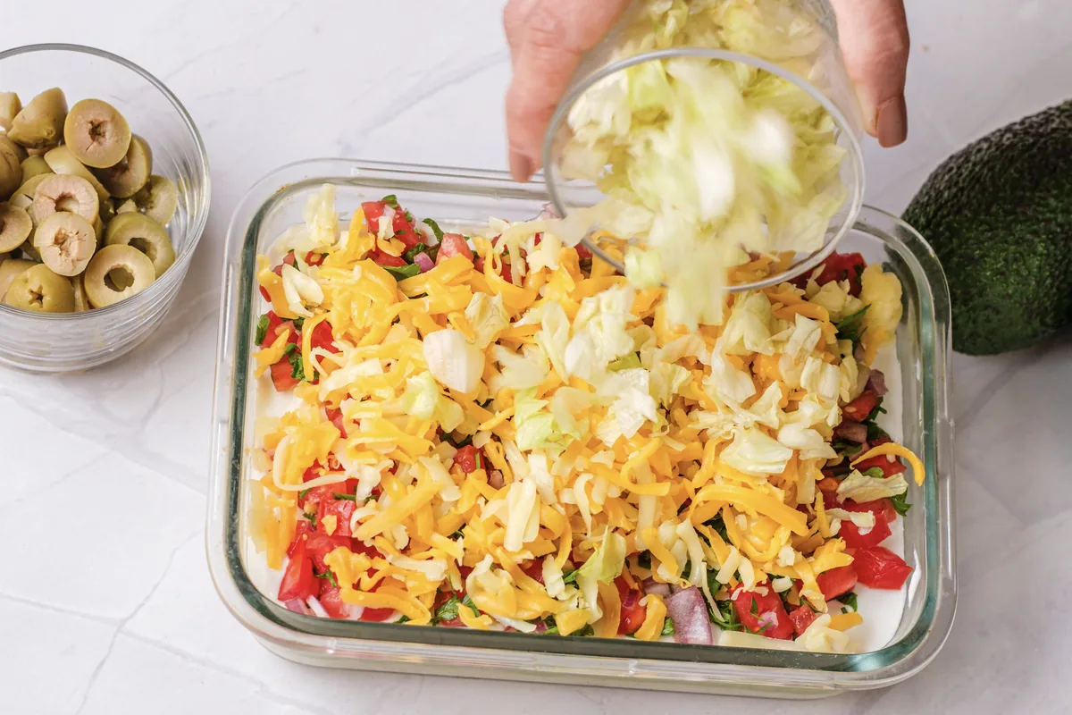 Adding shredded lettuce over the cheese layer