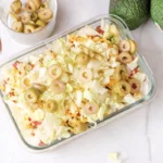 Finished 7 layer dip topped with sliced green olives in a glass dish