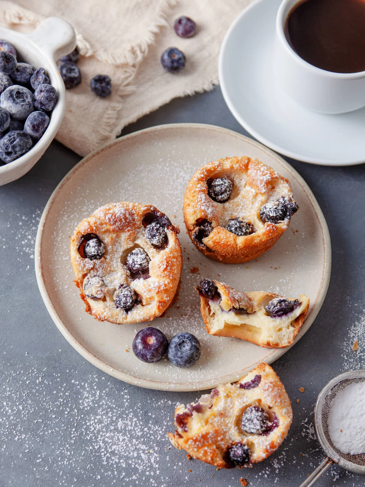 Blueberry popovers served with fresh blueberries and a cup of coffee.
