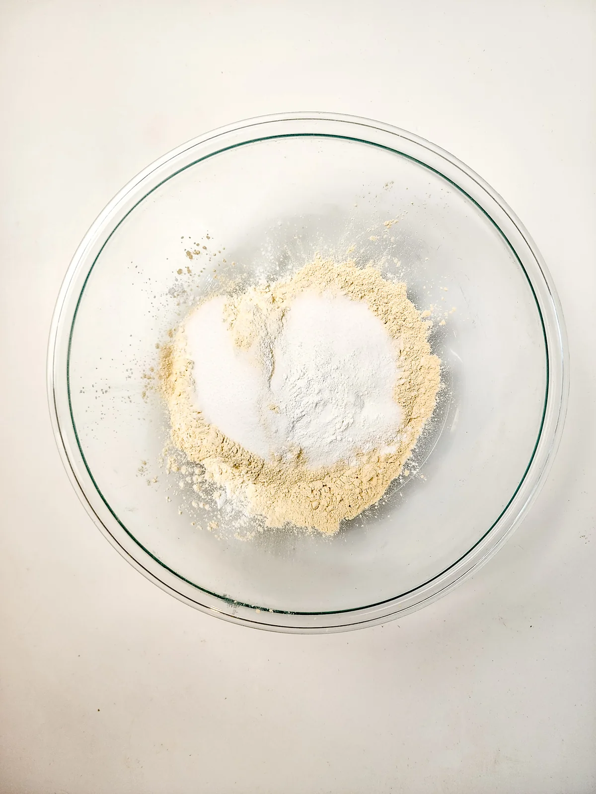 Flour, protein powder, sugar, and leavening in a glass mixing bowl.