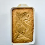 Golden baked blondie in a loaf pan before breaking it into pieces.