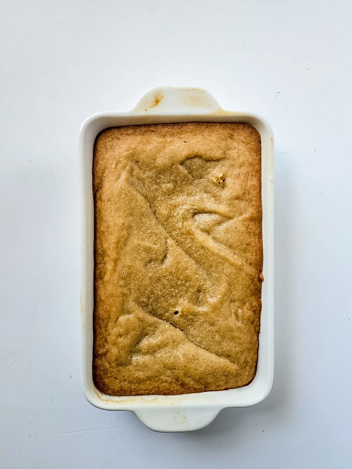 Golden baked blondie in a loaf pan before breaking it into pieces.