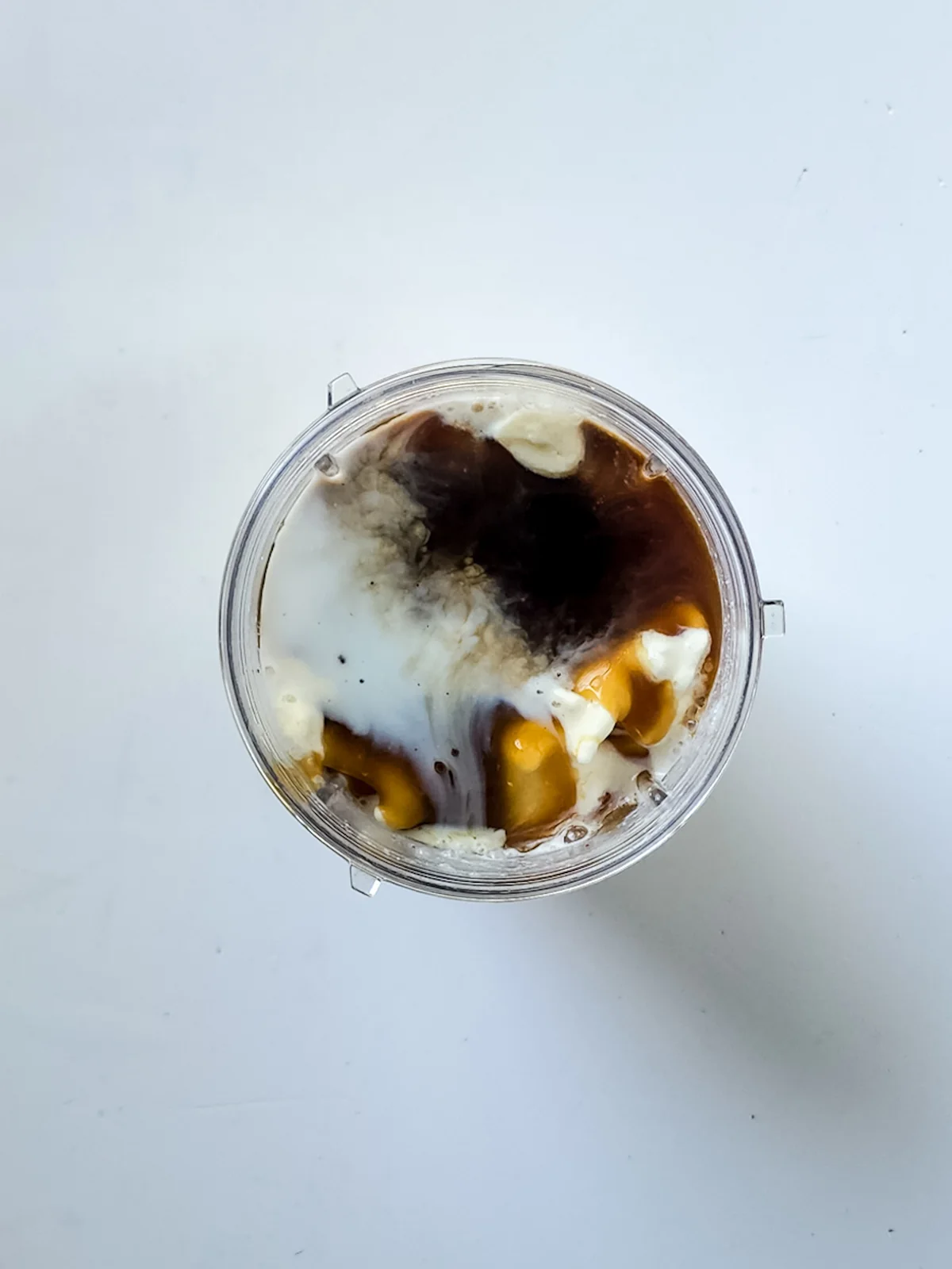 Vanilla ice cream, milk, caramel sauce, and butterscotch sauce in a blender before blending.