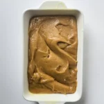 Thick blondie batter spread evenly in a loaf pan before baking.