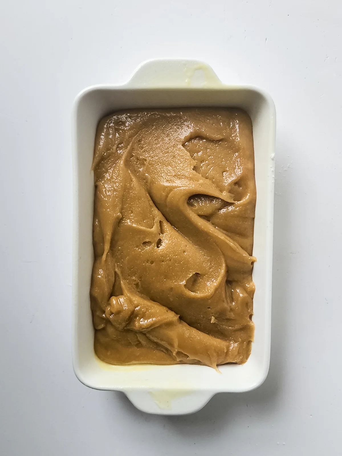 Thick blondie batter spread evenly in a loaf pan before baking.