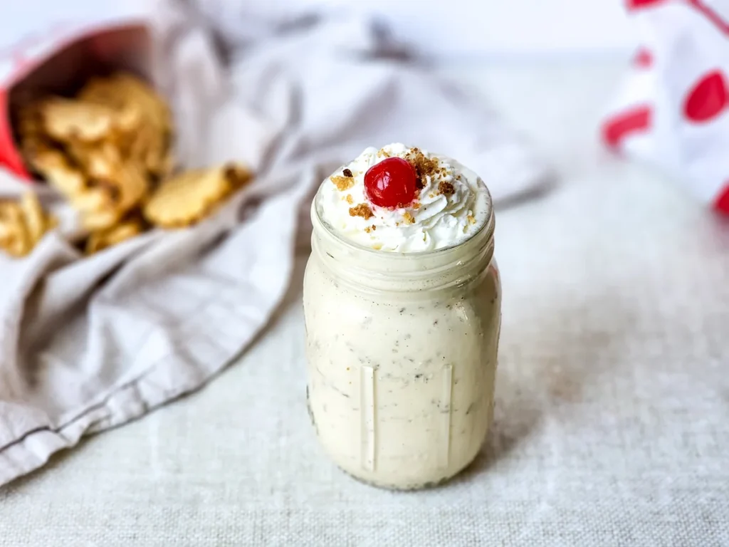 Overhead view of a caramel crumble milkshake topped with whipped cream, blondie crumbs, and a cherry.