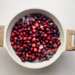 Fresh cranberries in water in a large pot before cooking.