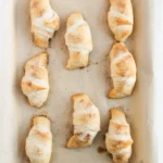 Easy Crescent Roll Churros With Dulce de Leche Golden baked crescent rolls on a parchment-lined baking sheet