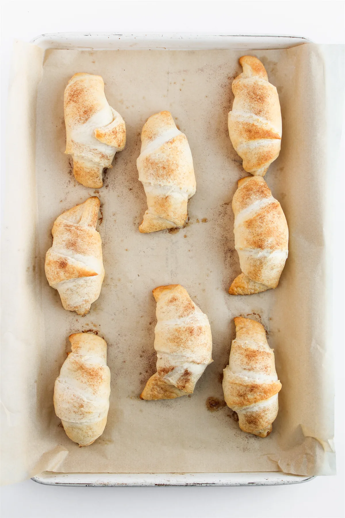 Easy Crescent Roll Churros With Dulce de Leche Golden baked crescent rolls on a parchment-lined baking sheet