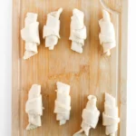 Easy Crescent Roll Churros With Dulce de Leche Crescent rolls rolled up around dulce de leche filling on a wooden board