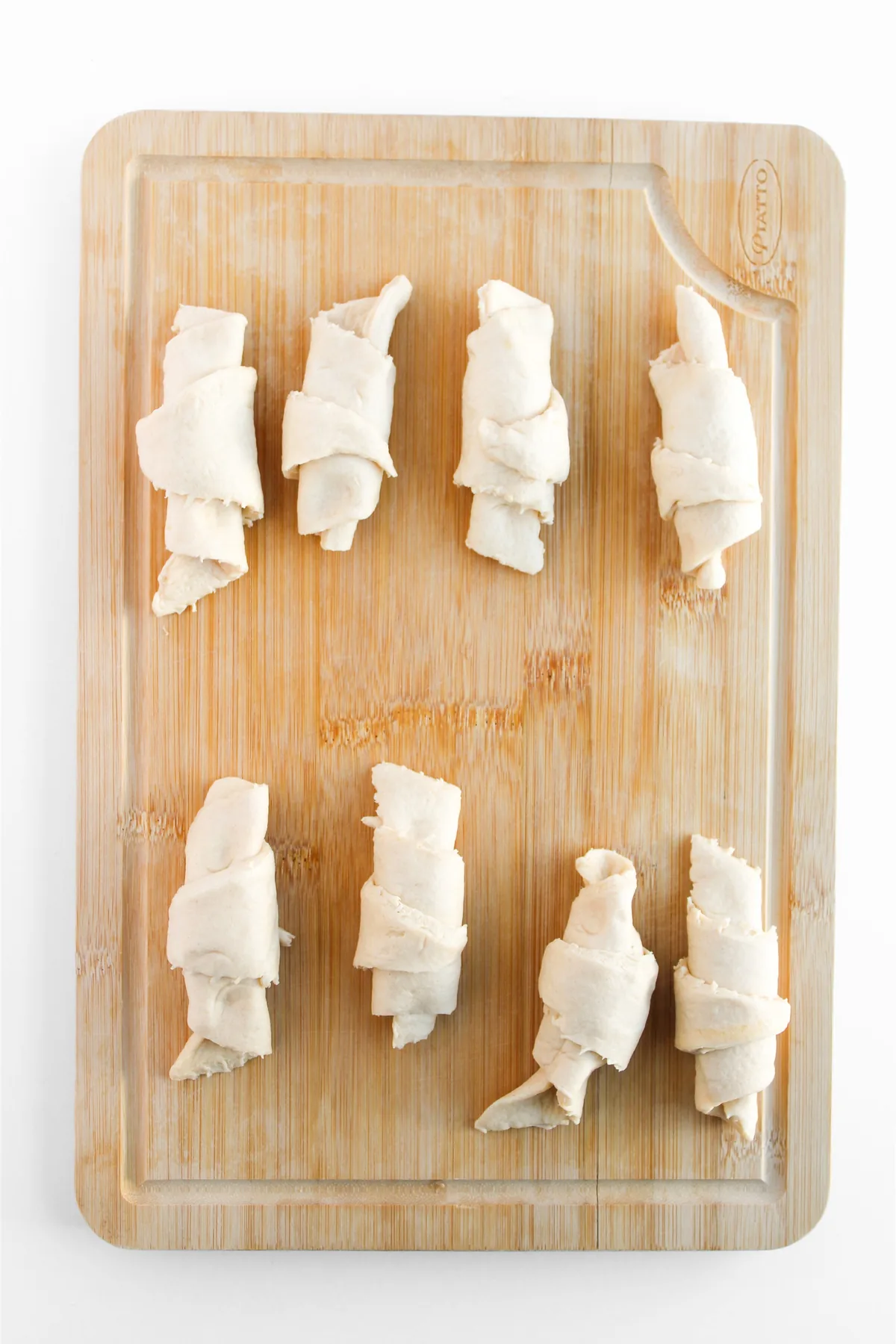 Easy Crescent Roll Churros With Dulce de Leche Crescent rolls rolled up around dulce de leche filling on a wooden board