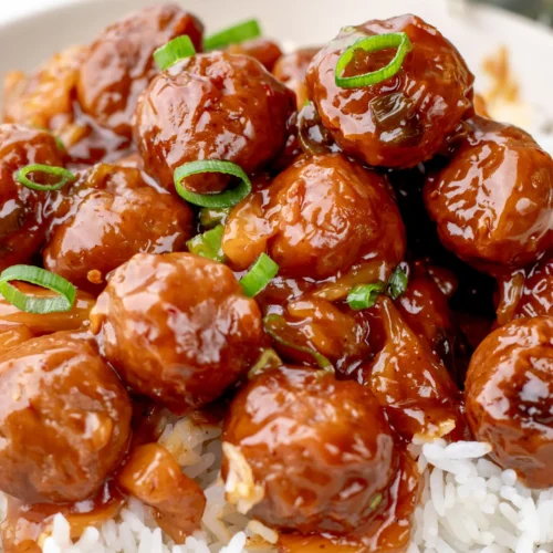 Spicy crockpot Hawaiian meatballs over white rice on a cream plate
