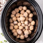 Frozen fully cooked meatballs in a black oval slow cooker