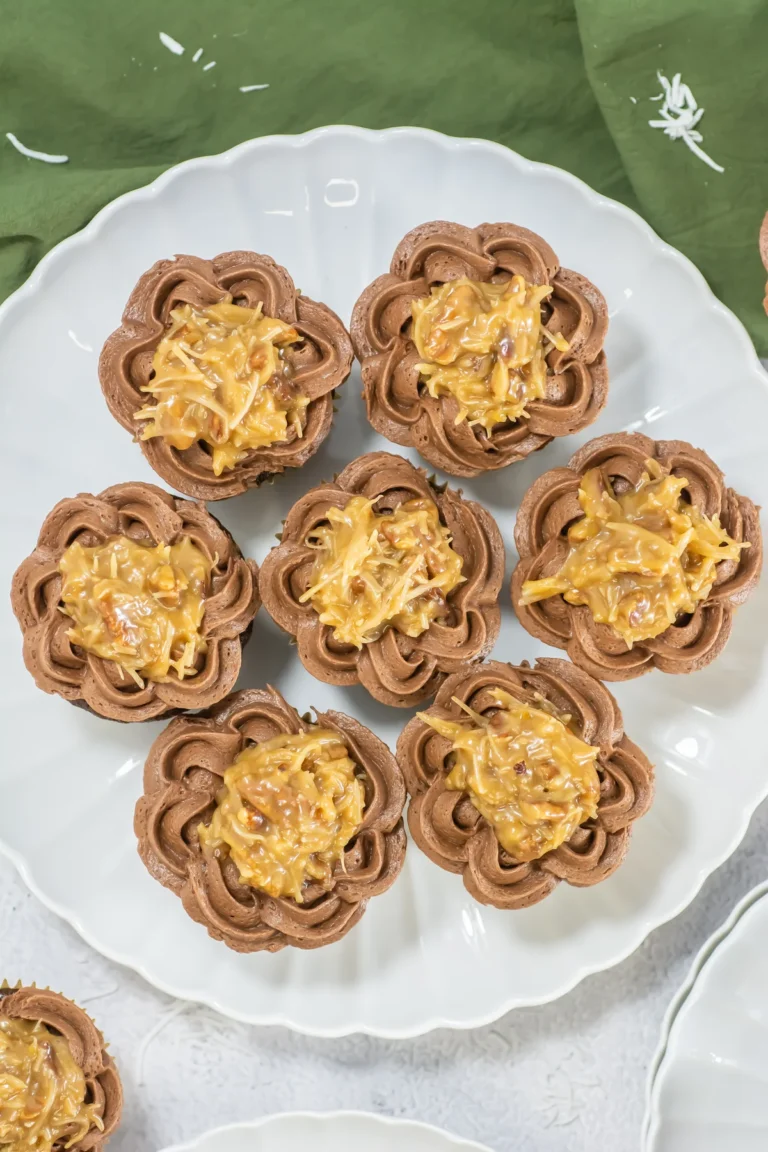 German chocolate cupcakes with coconut-pecan topping arranged on a white platter.