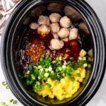 BBQ sauce, red chili flakes, sliced green onions and pineapple chunks on top of frozen meatballs in a slow cooker