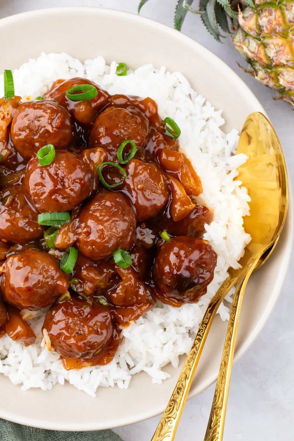 Hawaiian meatballs and BBQ pineapple sauce served over white rice with a gold spoon