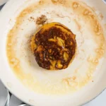 Cinnamon roll French toast flipped in the skillet, showing a deep golden-brown side