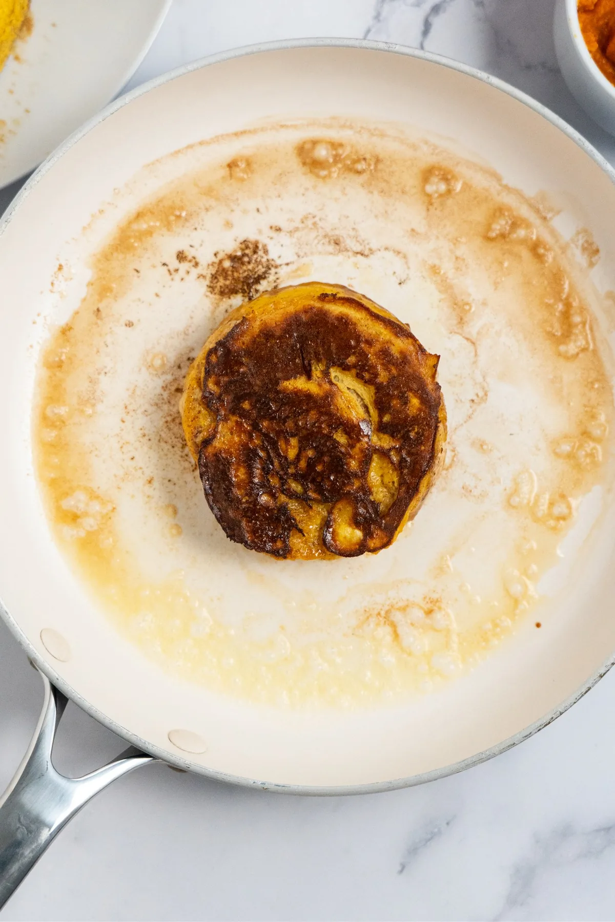 Cinnamon roll French toast flipped in the skillet, showing a deep golden-brown side