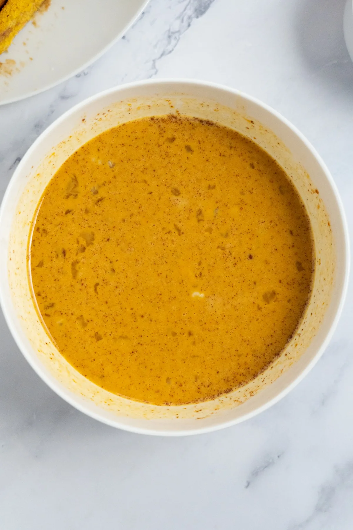 Pumpkin spice custard whisked smooth in a white bowl